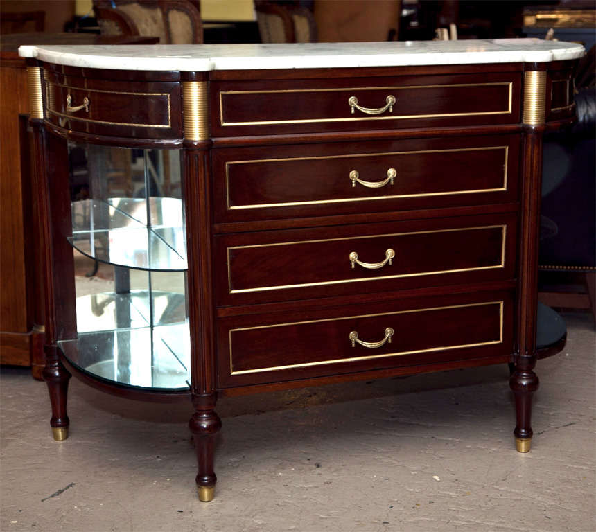 French Directoire style bow-front server, circa 1930s, the white half-moon marble atop a narrow frieze fitted with three drawers, over a three-drawer chest flanked by mirror-back glass shelvings on each side, raised on bulbous legs ending in brass
