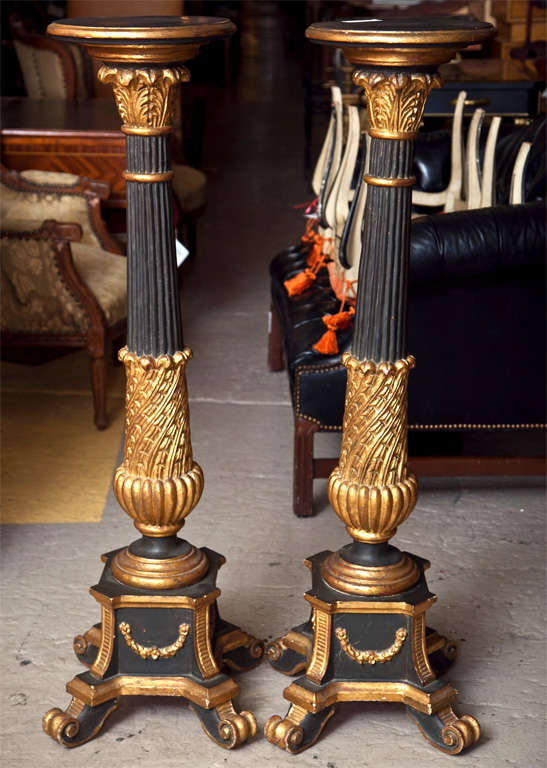 Pair of attractive ebonized and parcel-gilt pedestals, circa 1940s, the circular top supported by a fluted column headed by foliage capitol, ending in urn-like base with scrolled feet. Style of Maison Jansen.