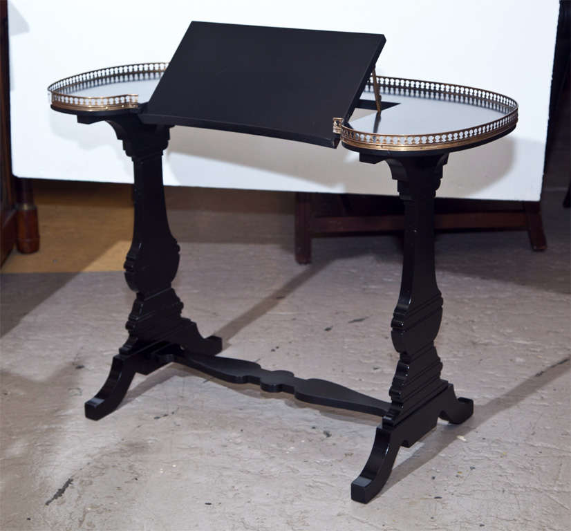 Kidney-shaped ebonized book or music stand, circa 1950s, the top with 3/4 brass gallery, the front part tilts up, supported by two pedestals with a single stretcher. In the manner of Jansen.