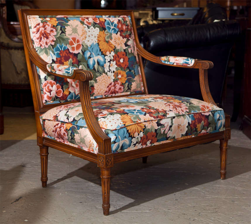 Pair of French Louis XVI style mahogany marquises, circa 1940s, the rectangular back with padded arms and seat, upholstered in floral fabric, raised on fluted tapering legs, ending in toupie feet.
