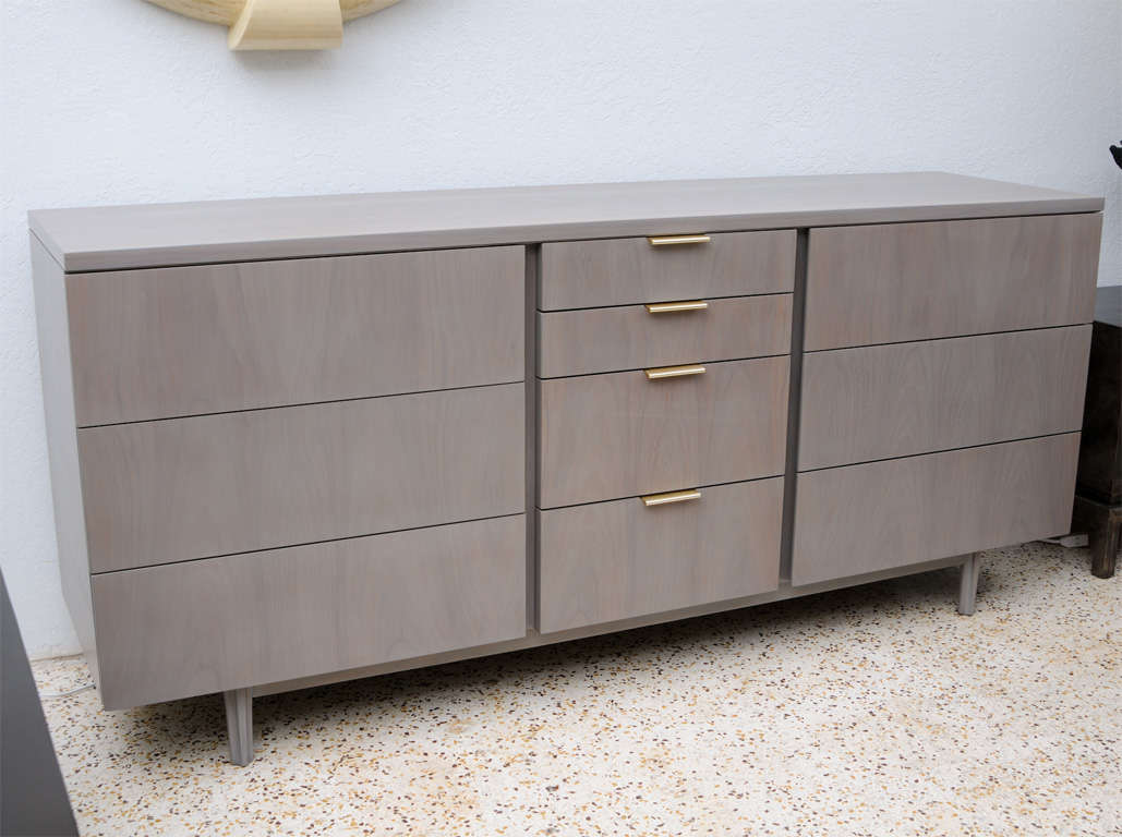 This mid-century walnut dresser for John Stuart has been given a sophisticated grey wash. The simplicity and subtle contrast of the original gold anodized aluminum pulls further enhances its handsome, clean-lined elegance. You will love this piece...