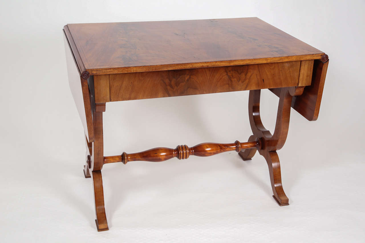 English mahogany writing table, with folding-leaf sides, and center drawer in apron. Trestle base with harp legs and turned center stretcher. Recently refinished French polish.

40
