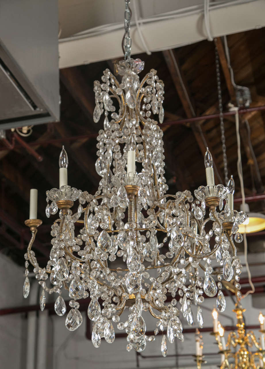 A grand vintage French Louis XVI style basket form crystal chandeliers, circa 1950s, having eight patinated gilt brass arms, decorated with crystal bobeches, discs, and crystal beading. Missing two crystal plates and some crystals.