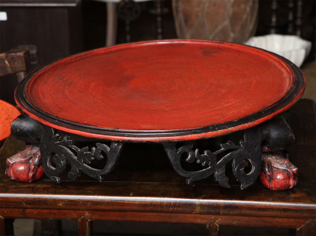 An offering table / server from Thailand with red top and black painted, hand-carved apron with ball and claw feet.