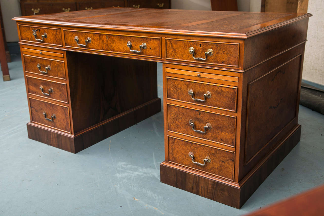 A three-piece, tan leather surface with tooling and gilding is the starting point for this three part pedestal desk in walnut burl. Classic touches abound in the appearance and construction of this handsome desk. A nod to modern desk use includes a