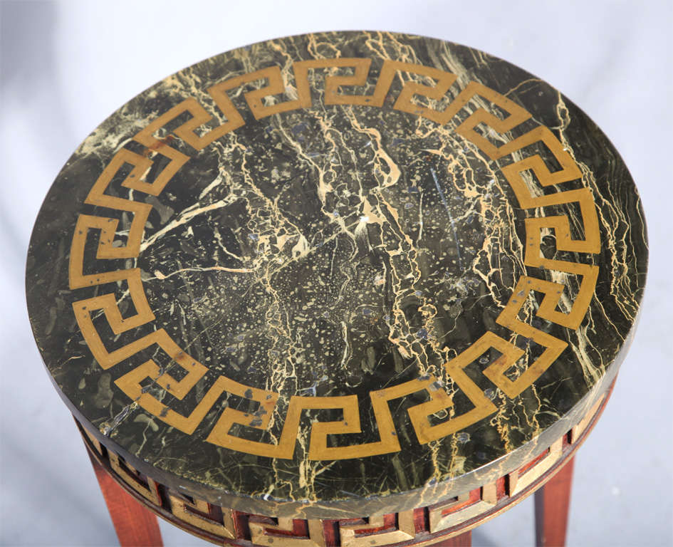Accent table, having a round top of marble decorated with Greek key, on mahogany base out-carved with matching gilded pattern, raised on square tapering legs.