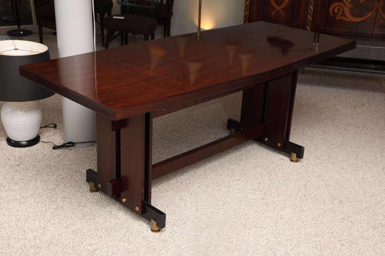 Architectural form with rosewood veneer, polished brass mounts, and black painted metal.  Rectangular top with bowed sides, and modernist trestle base.  A truly elegant table with industrial elements combined to create an exciting sculptural form.