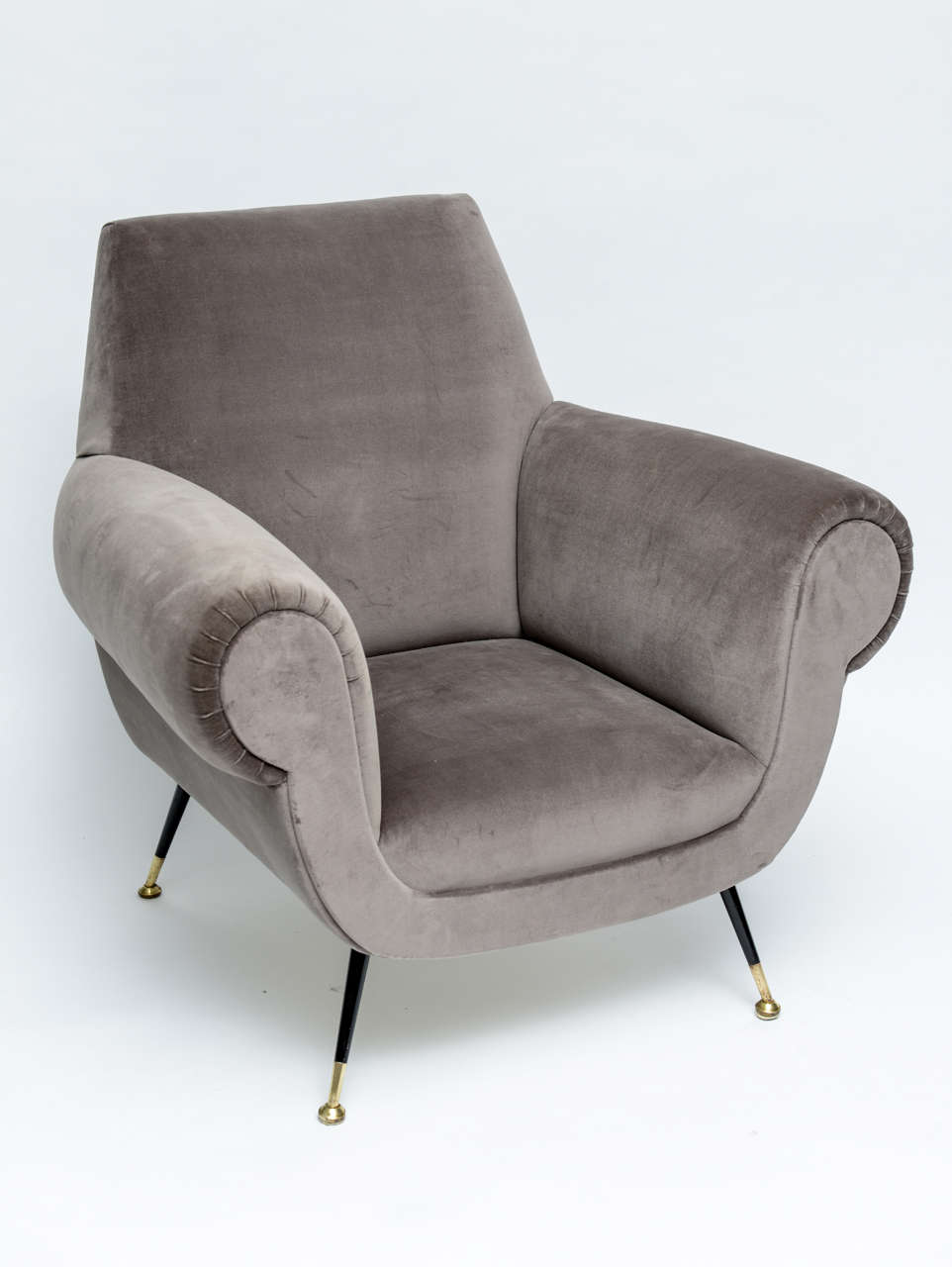 Let the deep seat and high arms of these handsome Italian lounge chairs envelop you in Continental comfort. Sexy and brooding in elephant-grey velvet upholstery, these masculine dandies - with their gloss-black enameled legs and polished brass