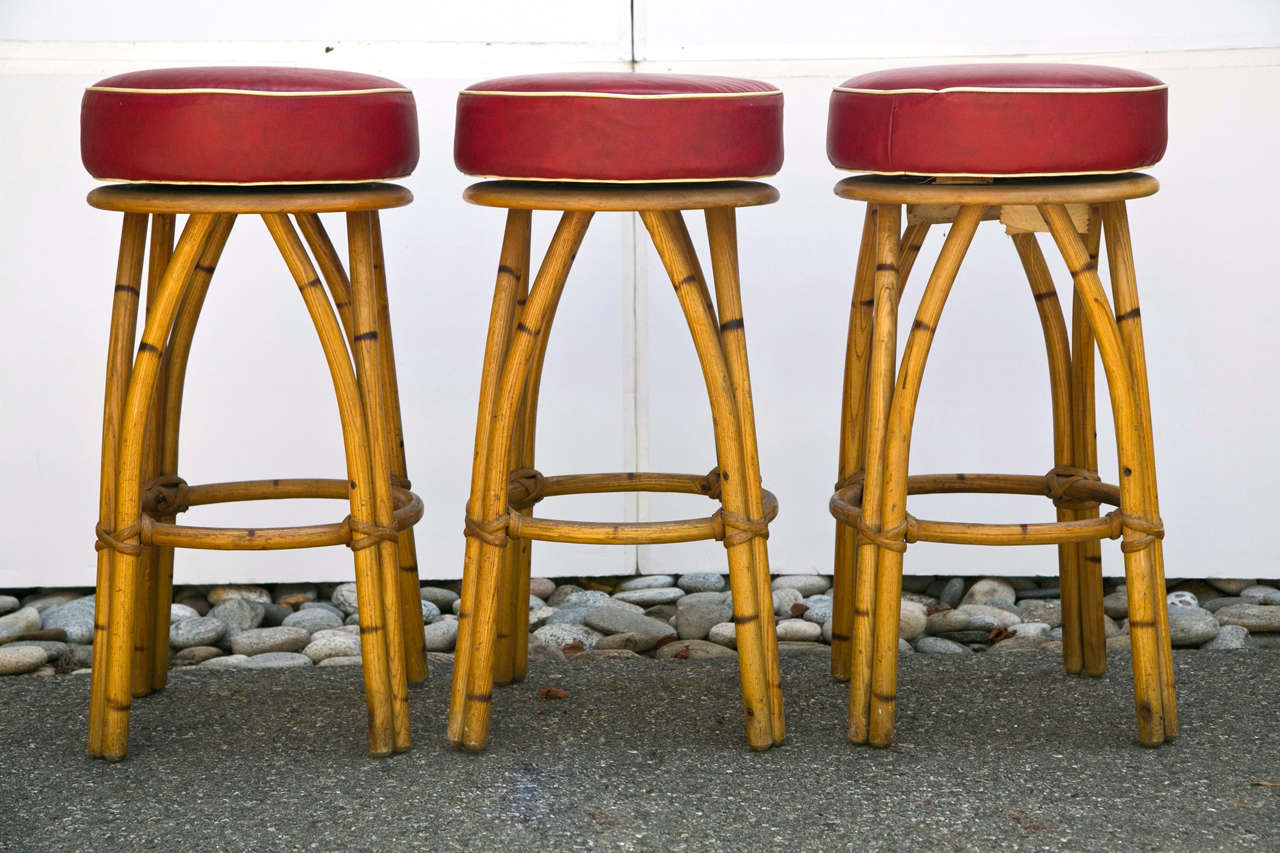 Heywood Wakefield Rattan Bar Stools with swivel seat covered in red vinyl with white trim.