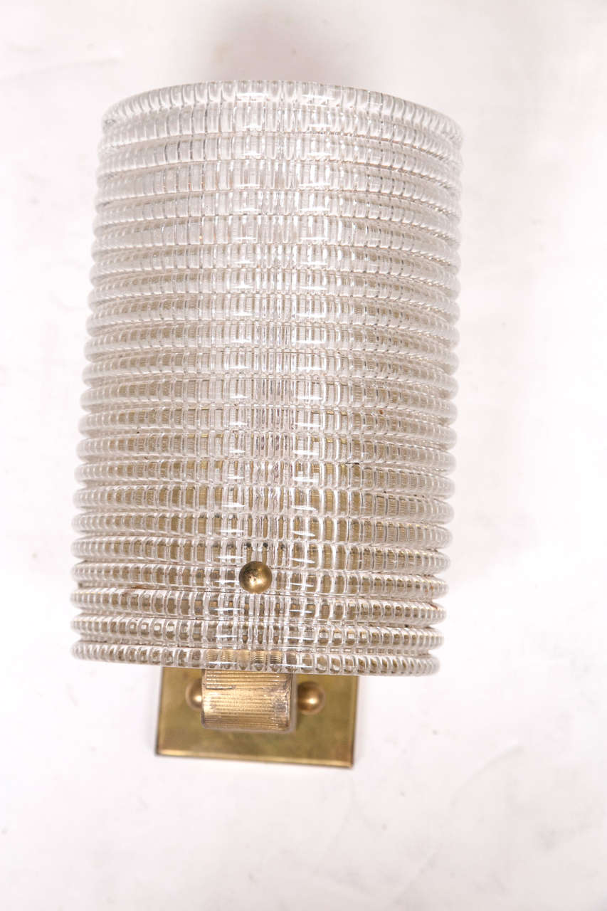 A pair of Italian grid patterned glass wall lights with a modern form gold tone metal arm and wall plate. All wiring is new for the US.