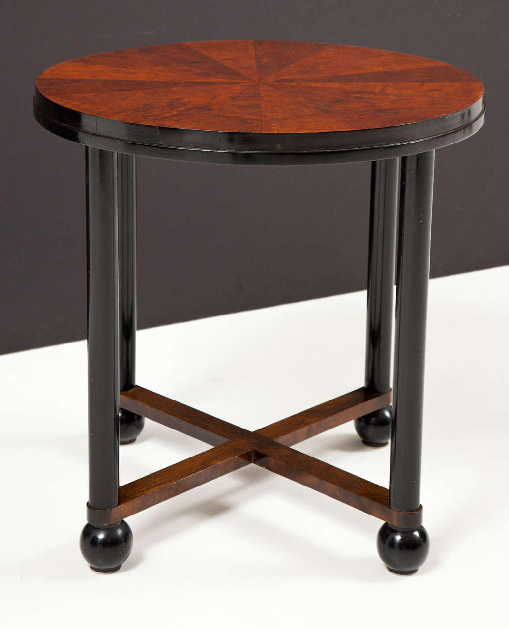 A Swedish birchwood and ebonized circular side table, circa 1930s. The circular top with pie shaped veneer supported by straight circular ebonized legs ending with ball feet joined by a low cross-stretcher.