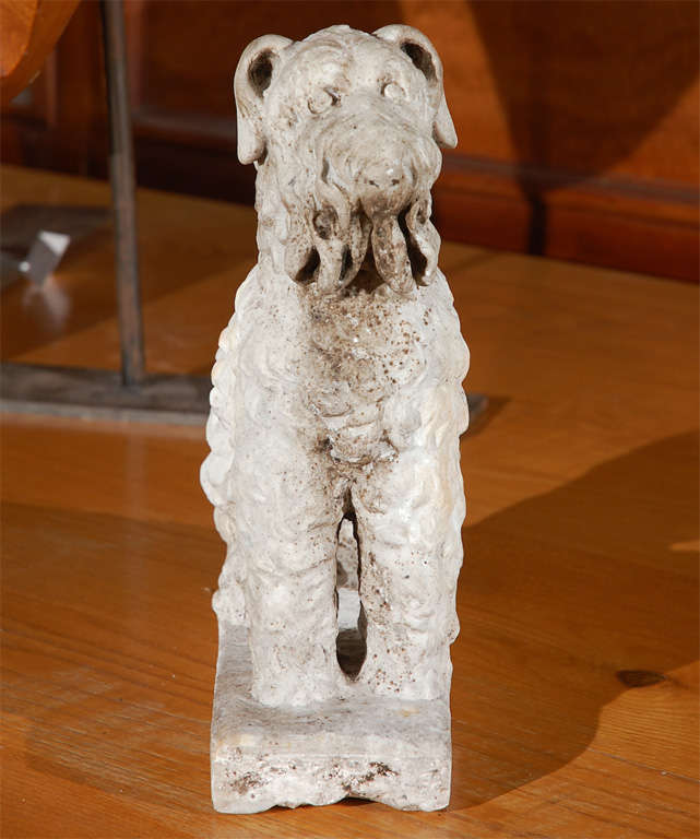 Carved marble seated dog with curly hair on a raised platform base