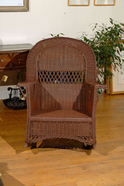 This is a very comfortable rocker.  It is painted brown.  The tighter woven reed complements the open back and unusual cut out below the arm rests.  This rocker is by Heywood Wakefield. Heywood Wakefield Company started in the late 19th Century