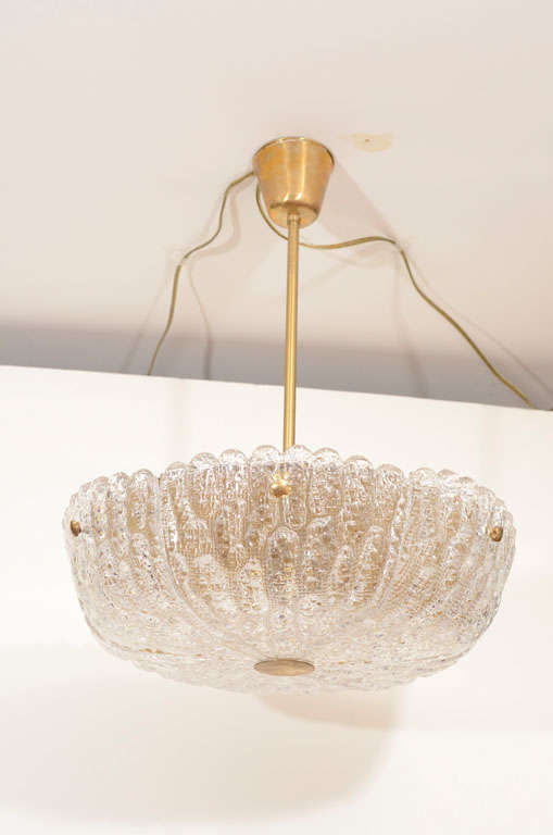 A sparkling fixture composed of six molded and pressed glass wedges affixed to a brass reflector with four-point shaped hardware and a centre disc.