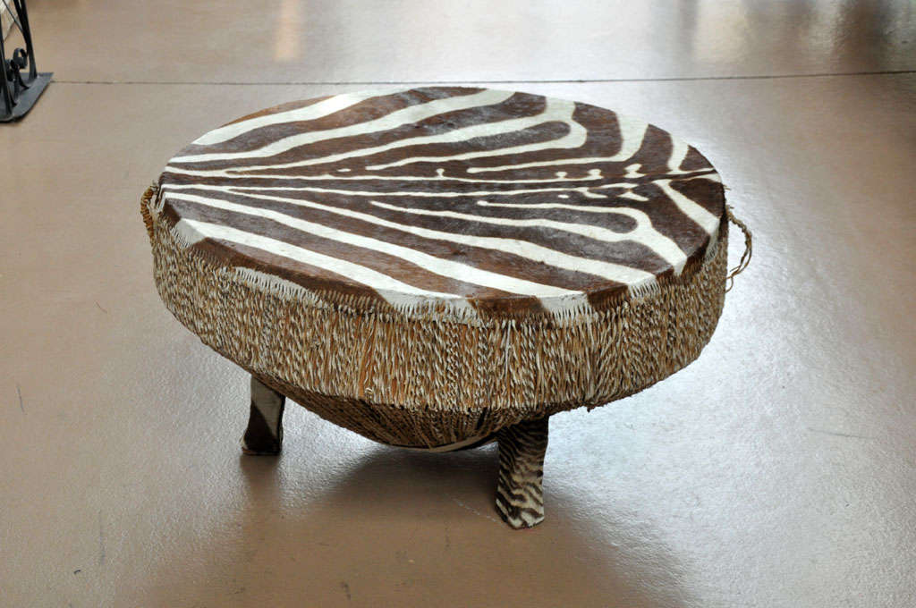 An African zebra hide covered drum table, with twisted hide down the sides and hide covered feet, circa 1950.
