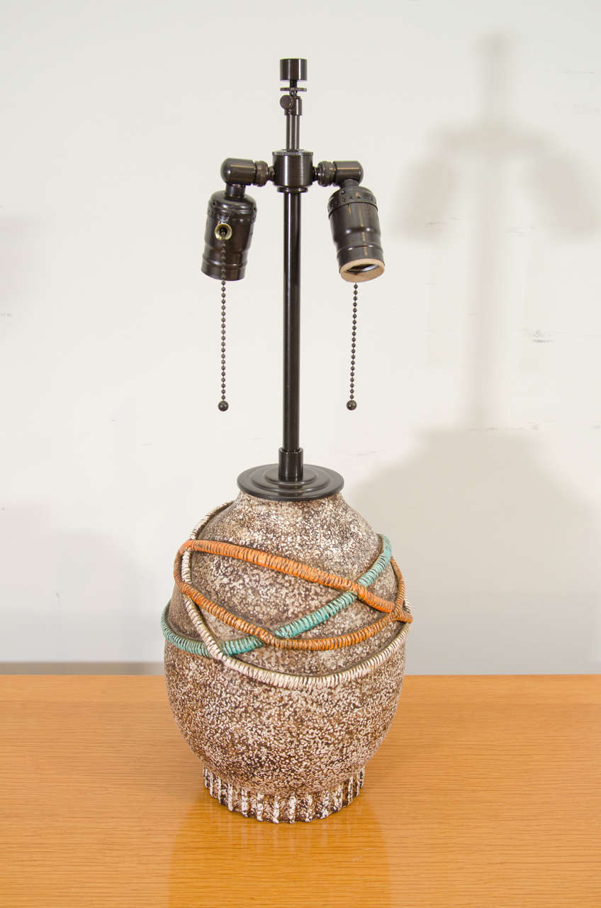 A ceramic lamp with cord motif supported on a flat vertically incised base, signed 