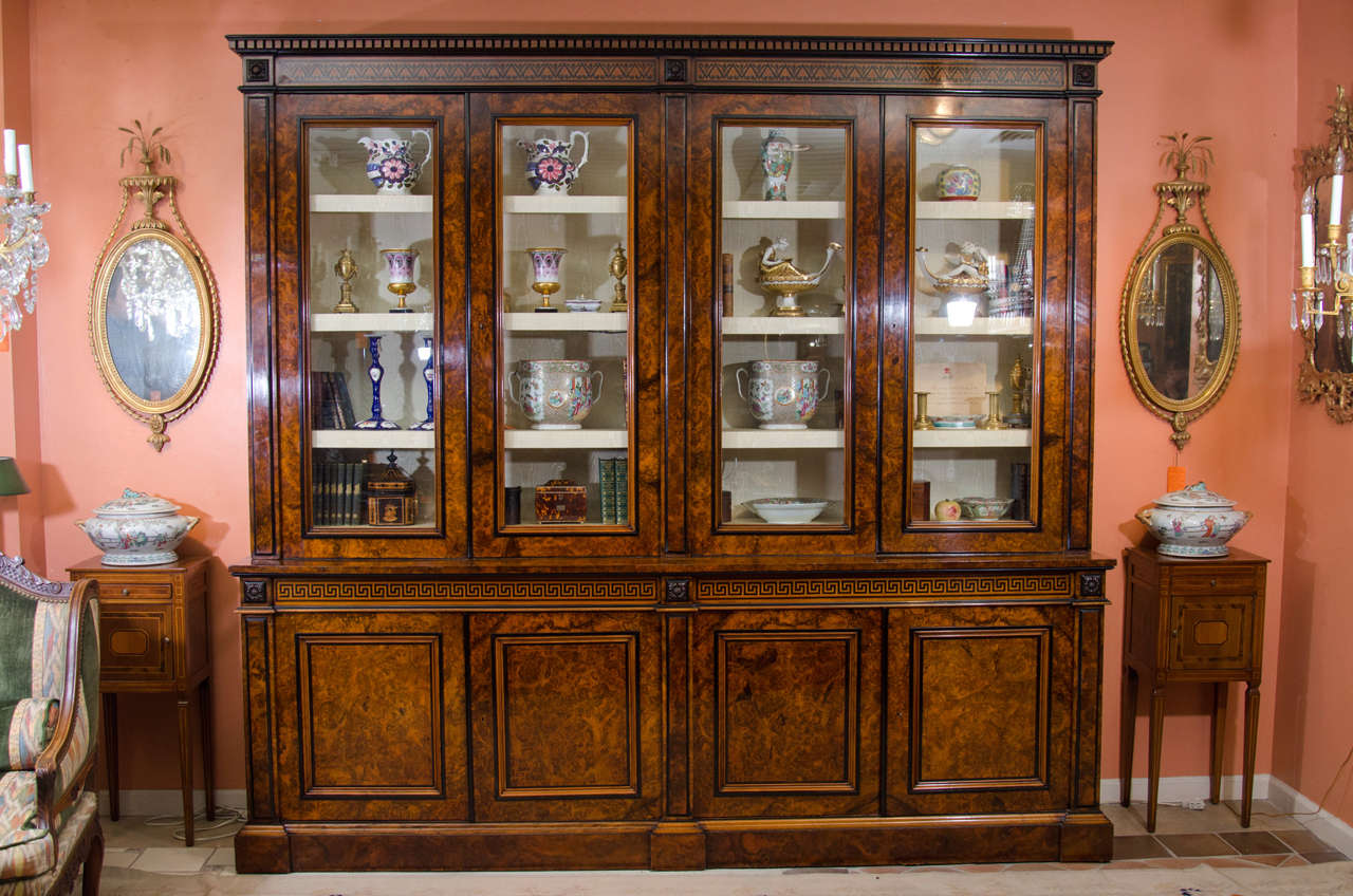 A very fine late Regency burl walnut and ebony inlaid bookcase with dental moldings, carved rosettes, ebony inlays and trim on a molded plinth base.