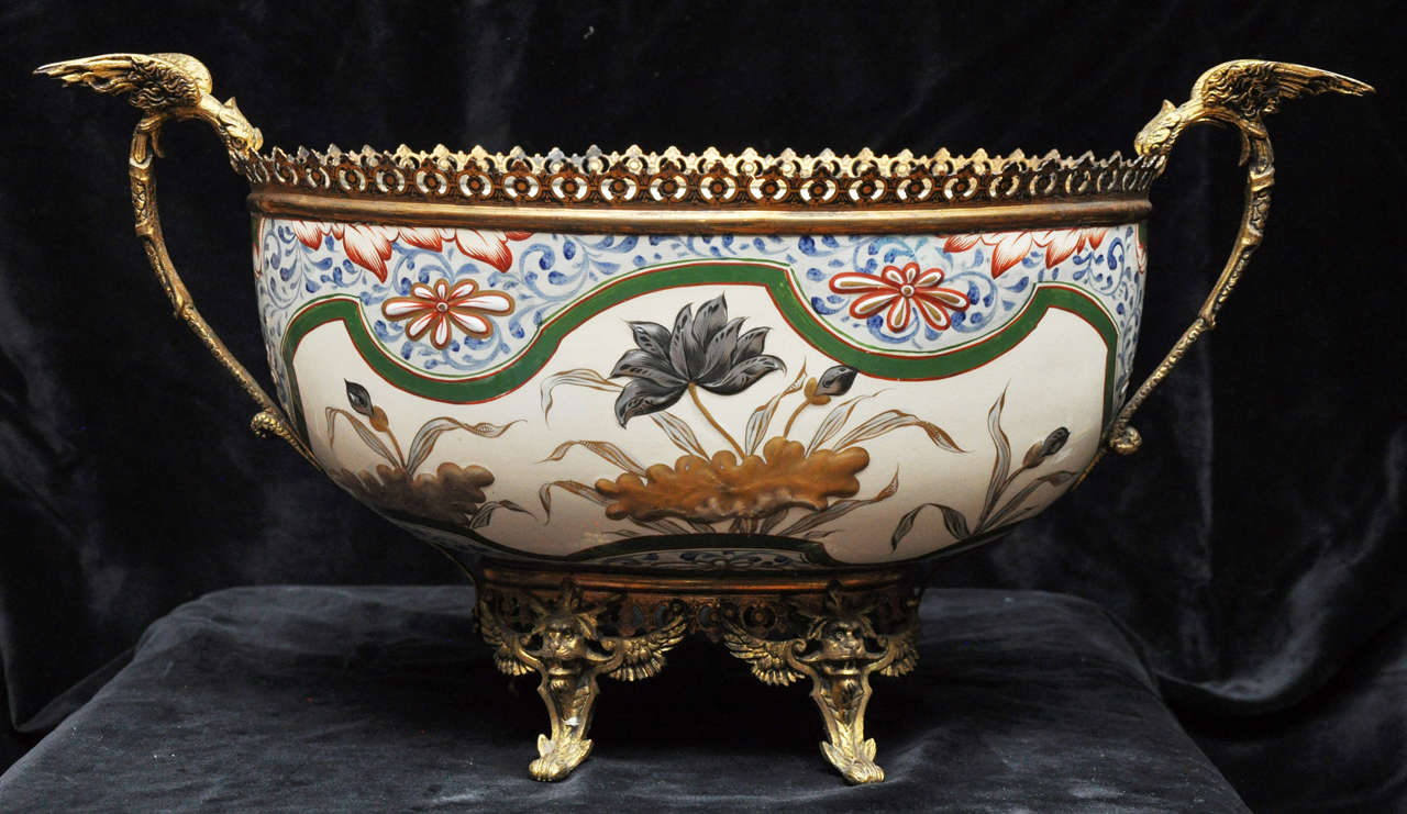 An outstanding, French hand-painted porcelain center bowl, having a blue, green paisley design at the rim punctuated with raised gilt and orange colored flowers and framed by an undulating green border. Just below the green ribbon like border are