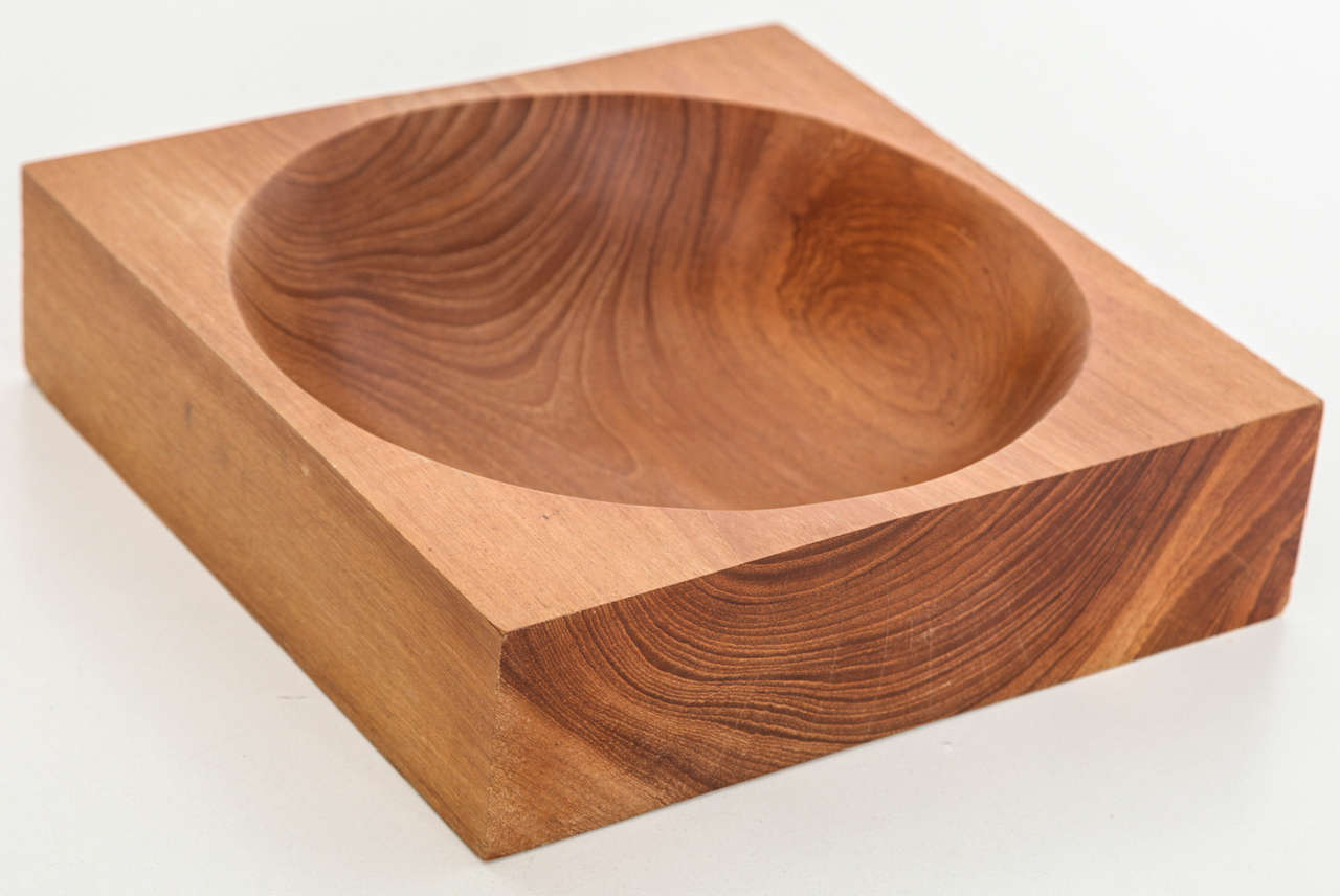 Square wooden bowl with round center, carved from a single piece of wood.