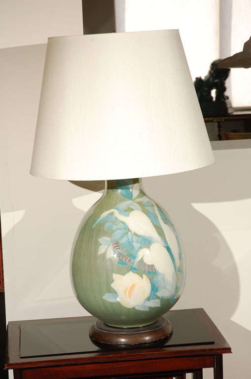Pair of elegant table lamps. Hand-painted ceramic body of green and blue coloring of cranes with white roses. Custom ivory silk shades and brass base.