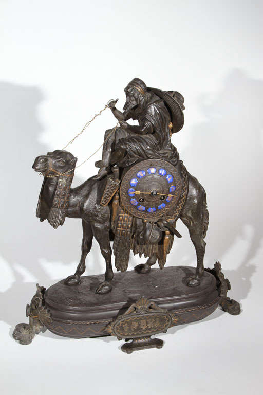 This is quite an unusual piece depicting a Bedouin, or Arab, man atop of a camel which is mounted with a clock upon an ovate base. The  8-Day time & strike clock is signed 