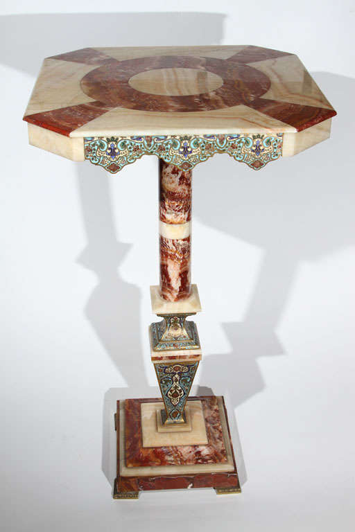 Outstanding decorative table with alternating cream and rouge onyx accented by scalloped champleve enamel panels. Pedestal of onyx and champleve enamel is mounted upon a square two tone onyx foot. Table top is removed by a single bronze post