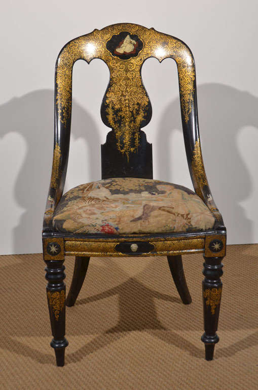 a curved back black lacquer and gilt finish papier mache chair with turned front legs, gilt swirls decorate the chair's frame including the splat and legs, small paintings of women accent the cartouches on the crest and side rails, 

the