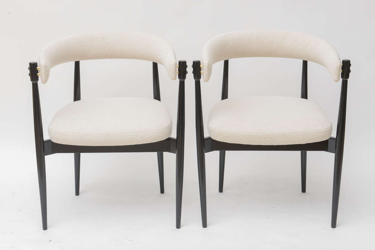 Pair of Danish horseshoe chairs in the manner of Nanna Ditzel. Fully restored with black lacquered frames and polished brass spacers. Beautifully upholstered in a soft, creamy white cotton bouclé.