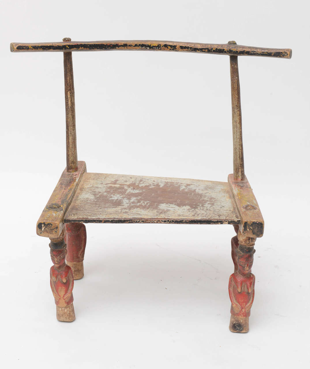 A wonderful chair, rich in patina and detail! Late 19th to early 20th century African chair, handmade by the Senufo people of Ivory Coast. Male and female painted and carved legs, remains of of original red, black, yellow and grey paint on seat and