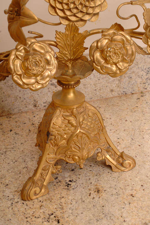 A gilt bronze candelabra decorated with Maddona lilies, roses, and chrysanthemums.
