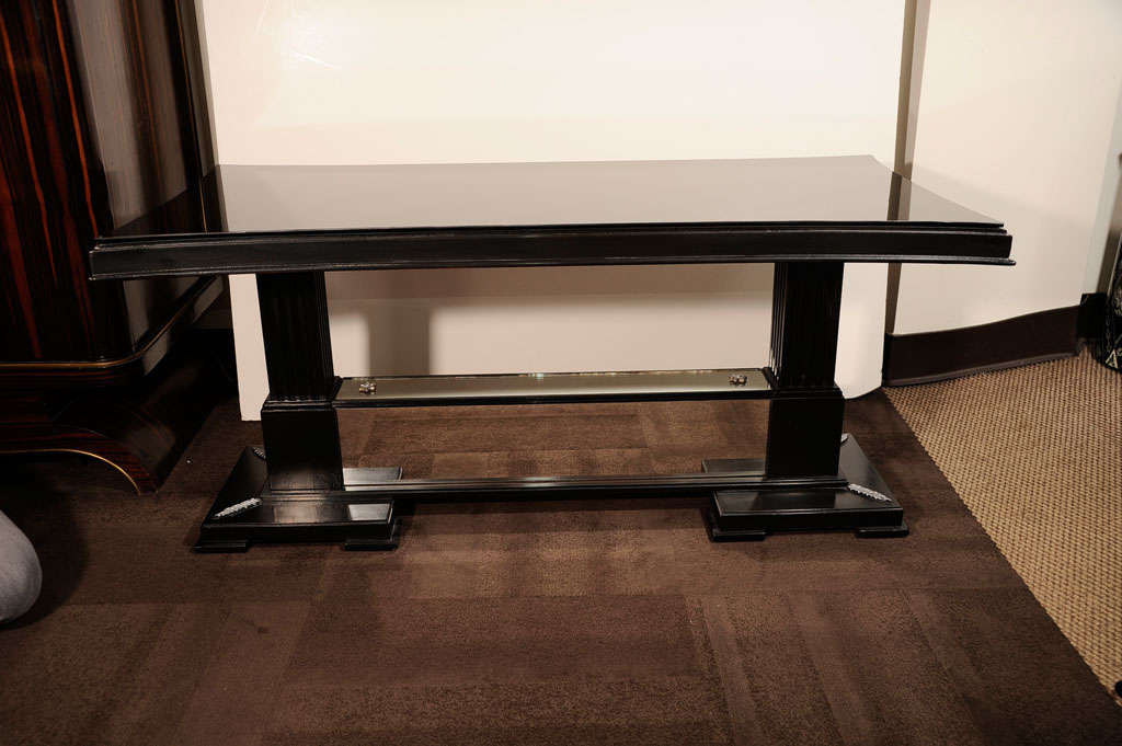 This beautiful Art Deco/Hollywood cocktail table was designed by the illustrious 20th century visionary, James Mont, circa 1940. Realized in ebonized mahogany, the piece stands on a pair of skyscraper style square bases with acanthus leaf motifs