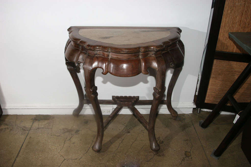 A blackwood demilune console or table with a marble inset top, Shanghai, 18th century. Bold scrolled carving on apron and legs.