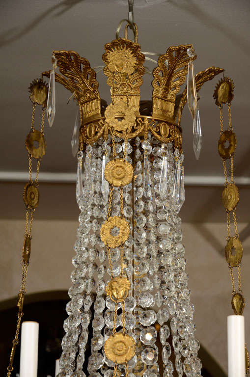 A fine Louis XVI gilt bronze and crystal eight light chandelier with palmette crown, medallions, figure and swags.