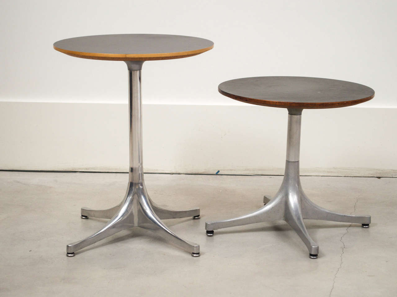 Two black side tables by George Nelson for Herman Miller. Features a micarta top and wood trim on an aluminum swag leg base.