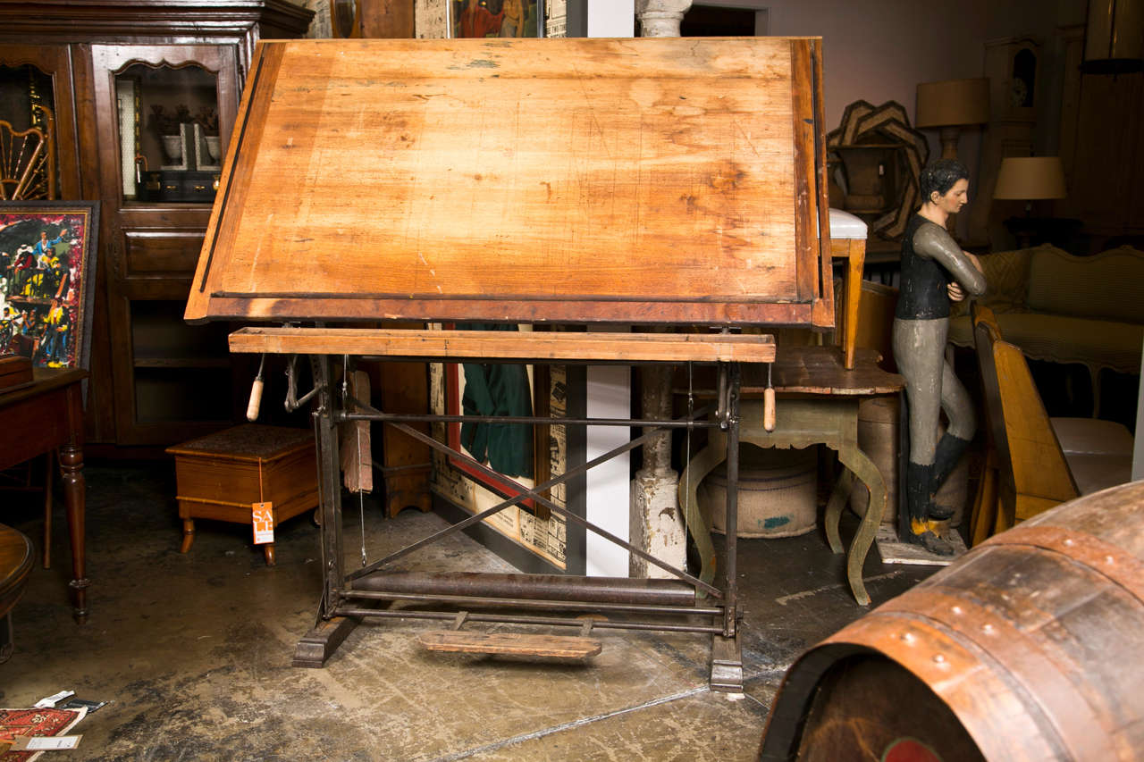 American beech wood drafting table with cast iron base and pine foot rest, c. 1900-40. The top height when flat is 36