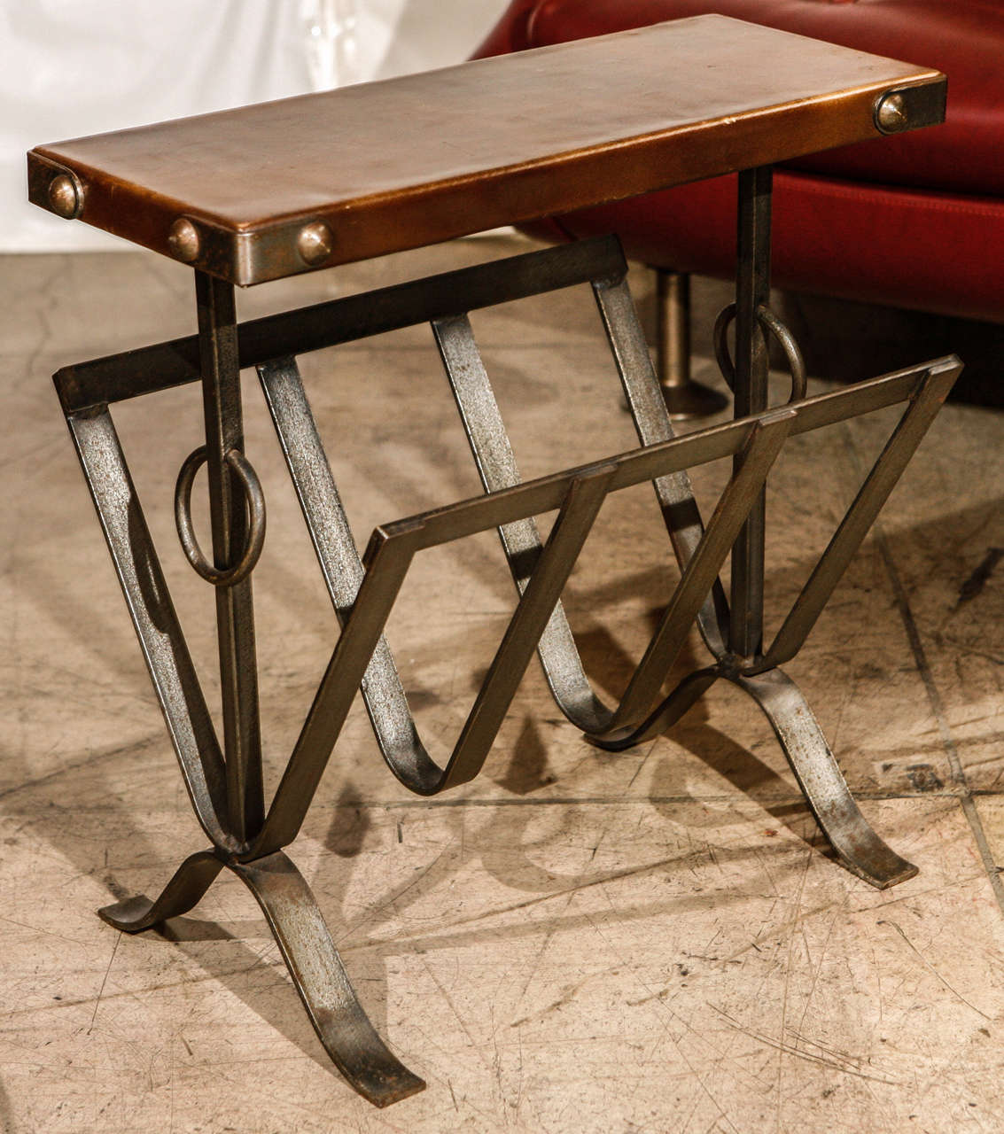 An amazing vintage magazine stand with table by Jacques Adnet. Made of wrought iron with a leather covered top.
