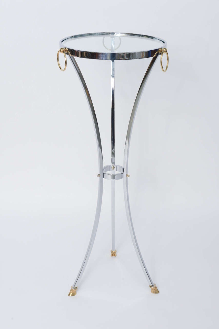 REDUCED FROM $2,250....Putting a modernist approach to Empire style, this elegant Maison Jansen pedestal table in chrome with solid brass detailing in the hoof feet and ring mounts. Thick glass insert top.
Measurements:  42 1/4 inches high  x  16