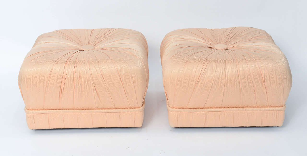 Glamorous and luxe, this pair of Hollywood inspired poufs is dramatic with their heavily pleated styling and large centre tuft, a souffle style. Original fabric in good order with a couple of light signs of age. On casters and easily movable, they