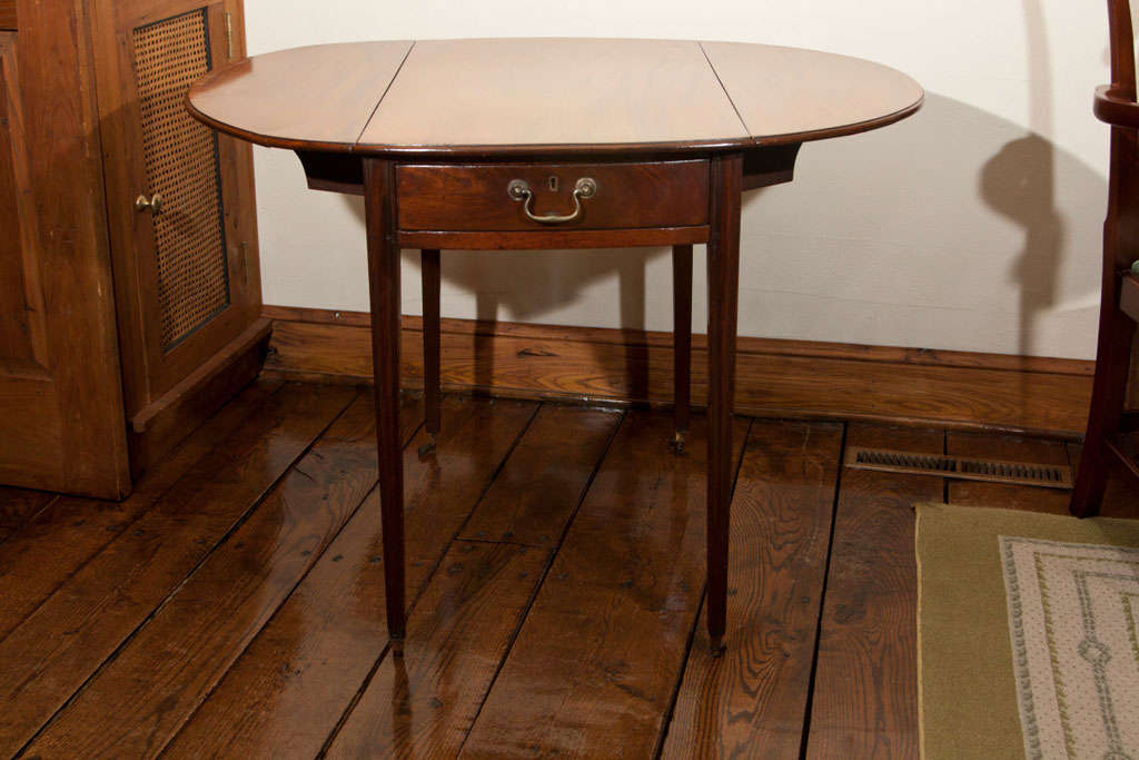 This fine little oval Pembroke table has all the desirable qualities one looks for in such a table. The Cuban mahogany top is delicately banded in kingwood, the drawer and apron are bowed at the same curve as the top and the legs are tapered and