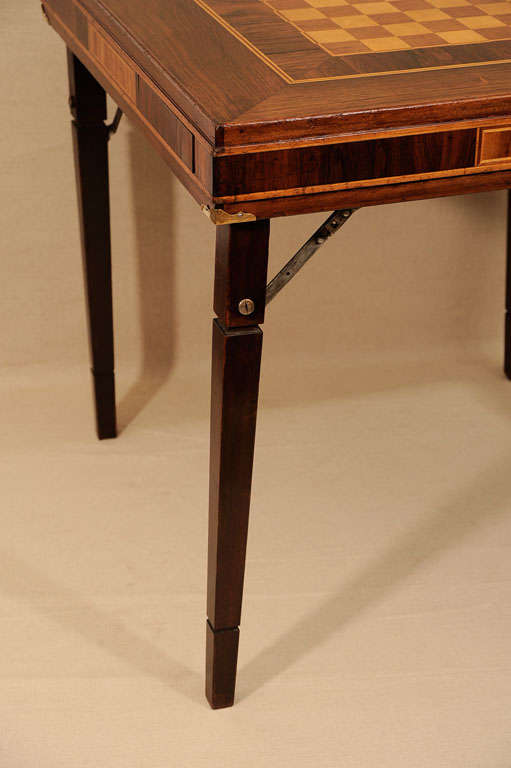 Distinctive Folding Campaign Game/Chess Table in Finely-Inlaid Mahogany, Rosewood and Satinwood Veneers with Two Felt-Lined, Spring-Loaded Hidden Drawers and Brass Detailing.  England, Early 20th Century.<br />
<br />
30 inches wide x 30 inches