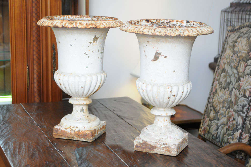 Classical pair of cast iron urns with original paint and patina.