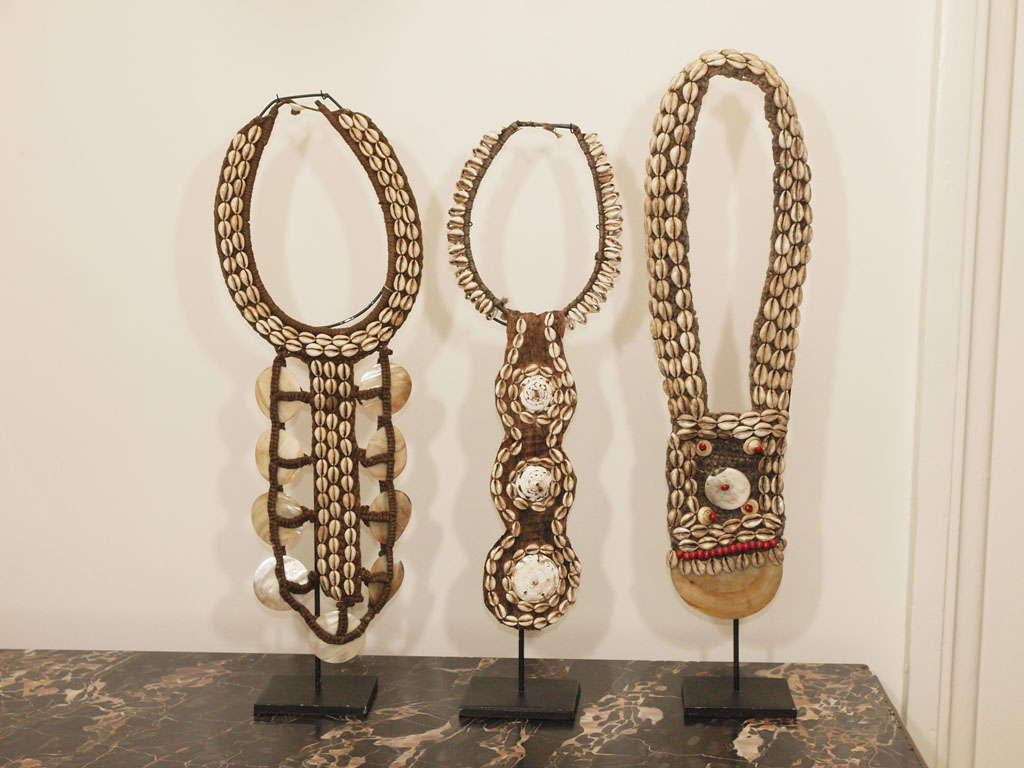 Asmat tribal necklace of  raffia and shell mounted to custom stand; pictured at right; necklaces at left and center have been sold; base measures 5