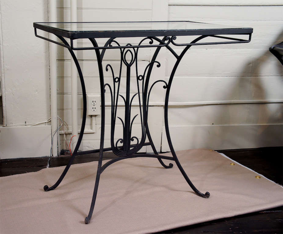 A matched pair of iron console tables, with stylized floral motif. Finely detailed hand wrought iron, with glass tops. The craftsmanship is exquisite.