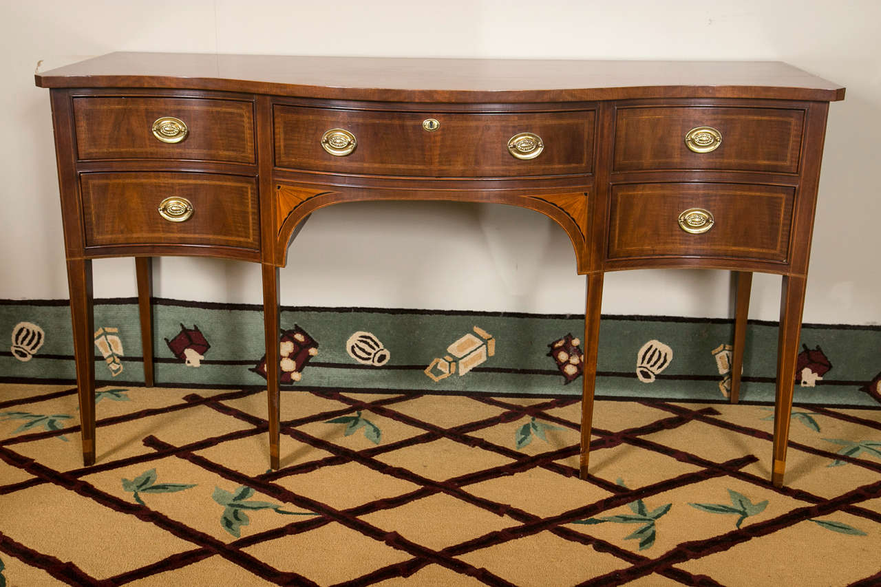An exquisite Georgian satinwood inlaid and crotch mahogany sideboard on long tapering legs. This custom quality, stamped by the White Furniture Company, finely made Hepplewhite sideboard has tapering legs supporting the finely inlaid mahogany case
