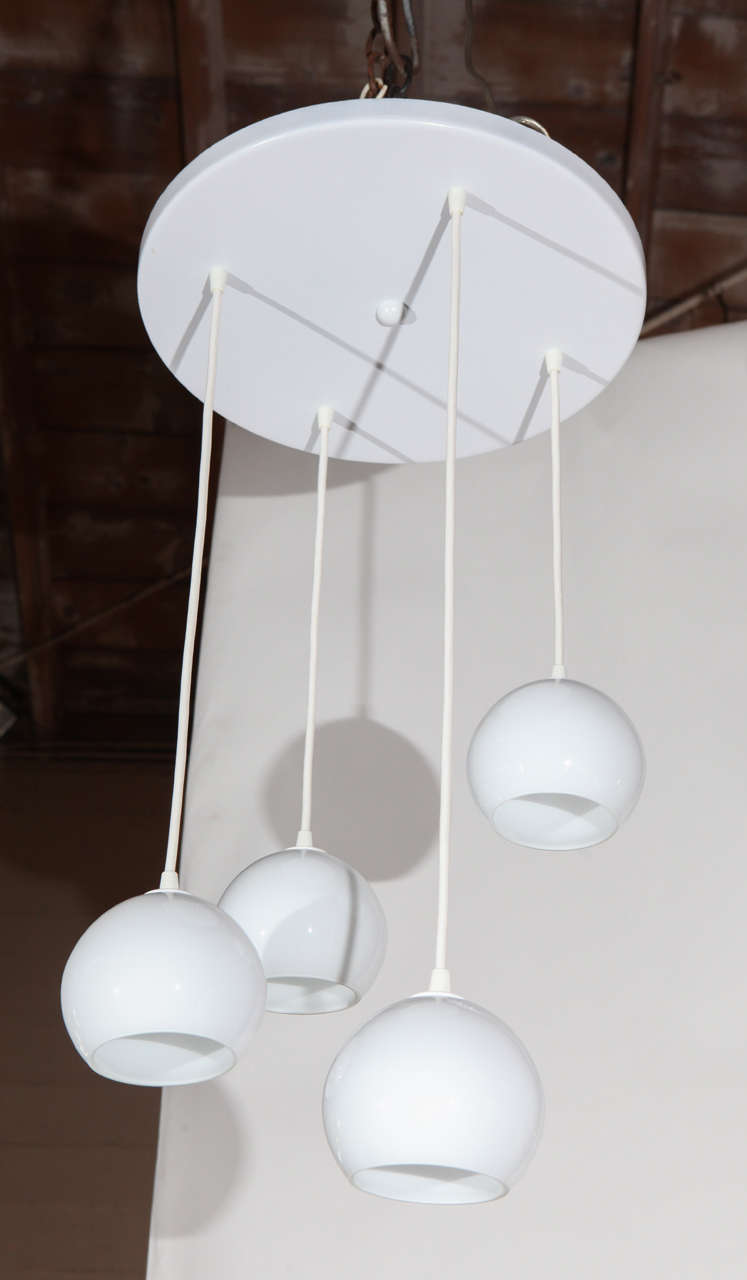Two midcentury four-light pendants. Each fixture has four suspended glass shades in varying lengths.