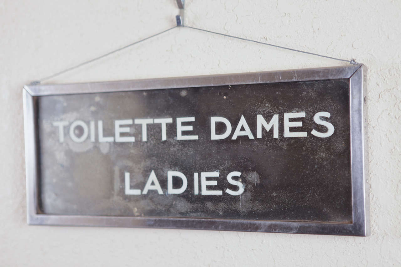French Art Deco  Toilette Dames Ladies Room Sign

Extremely well constructed heavy chrome framed and mirrored glass vintage sign.
Face and rear glass is clear, enclosing a mirrored glass plate with applied flocked lettering. All inside the chrome