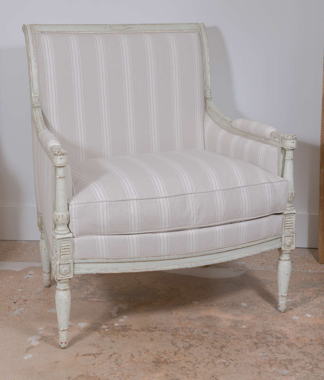 Pair of Painted Bergères hand-carved in the late 19th century in Directoire style. Later paint and newly upholstered in neutral stripes.