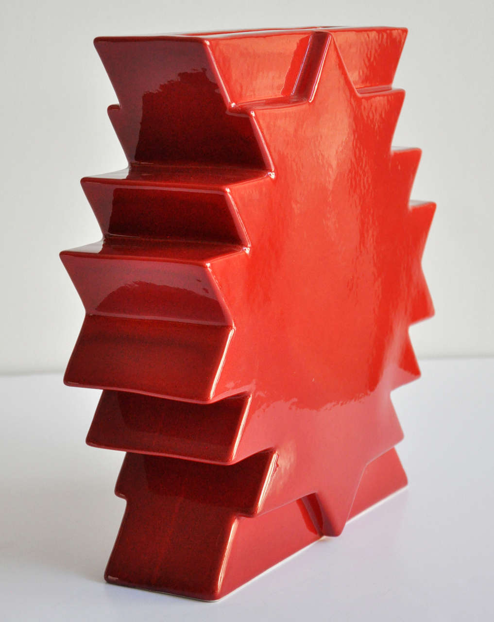 A red glazed ceramic vase by Memphis founder Ettore Sottsass from the Yantra di terracotta series. Manufactured by Edizioni Arte Design Agliana Pistoia Italia. Marked Sottsass Y/28. Maker's decal (EAD) on underside.

Reference: Ettore Sottsass
