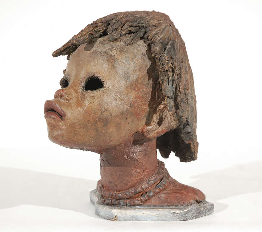 An expressive and striking hand sculpted bust of an African girl by an unknown artist Hollow construction mounted on original painted wood base.