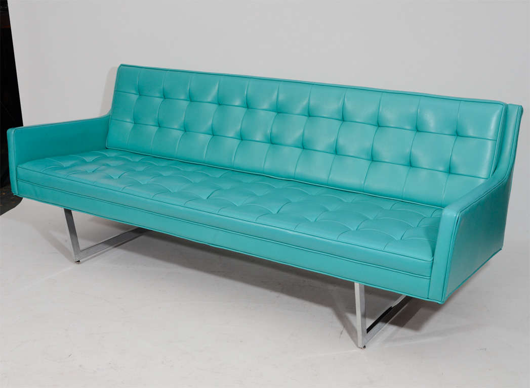 Sleek tufted sofa with great lines and profile. Floating on angled chrome supports, it is upholstered in its original aqua colored vinyl from 1968. Two available.
